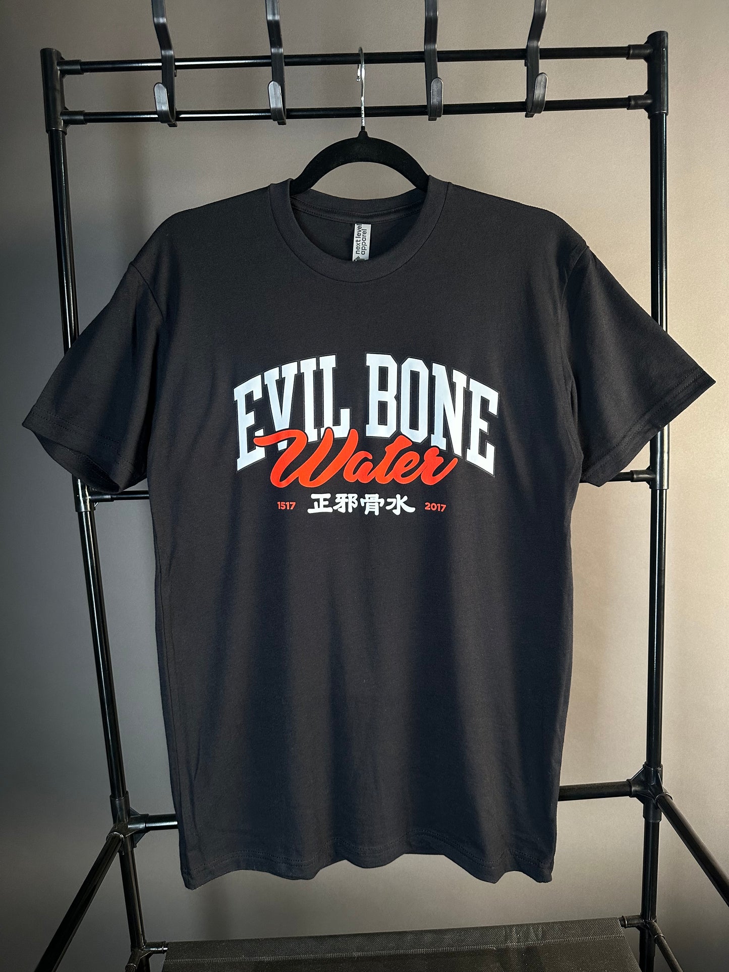 Black t-shirt with 'Evil Bone Water' text on a metal rack against a neutral background