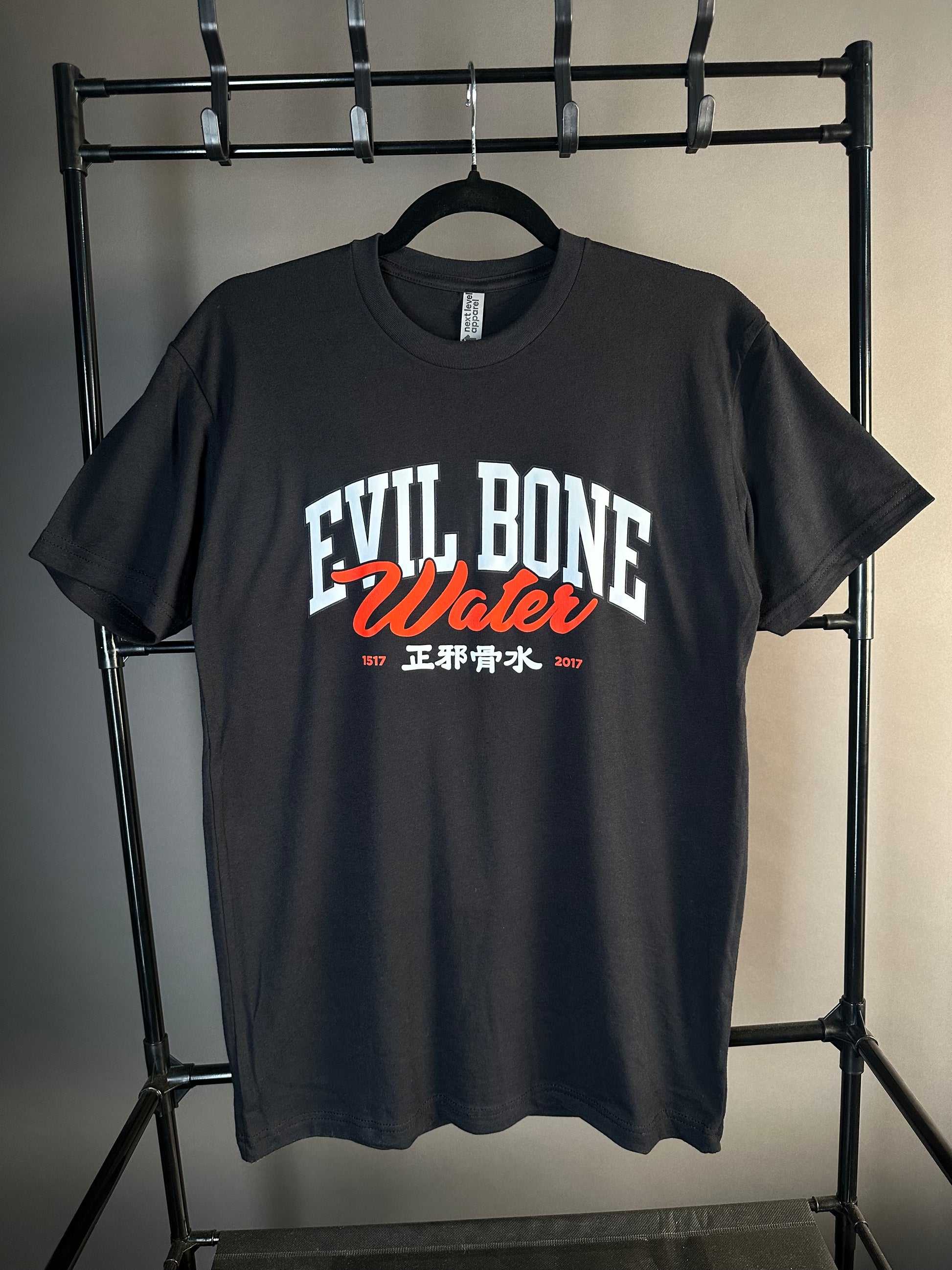 Black t-shirt with 'Evil Bone Water' text on a metal rack against a neutral background